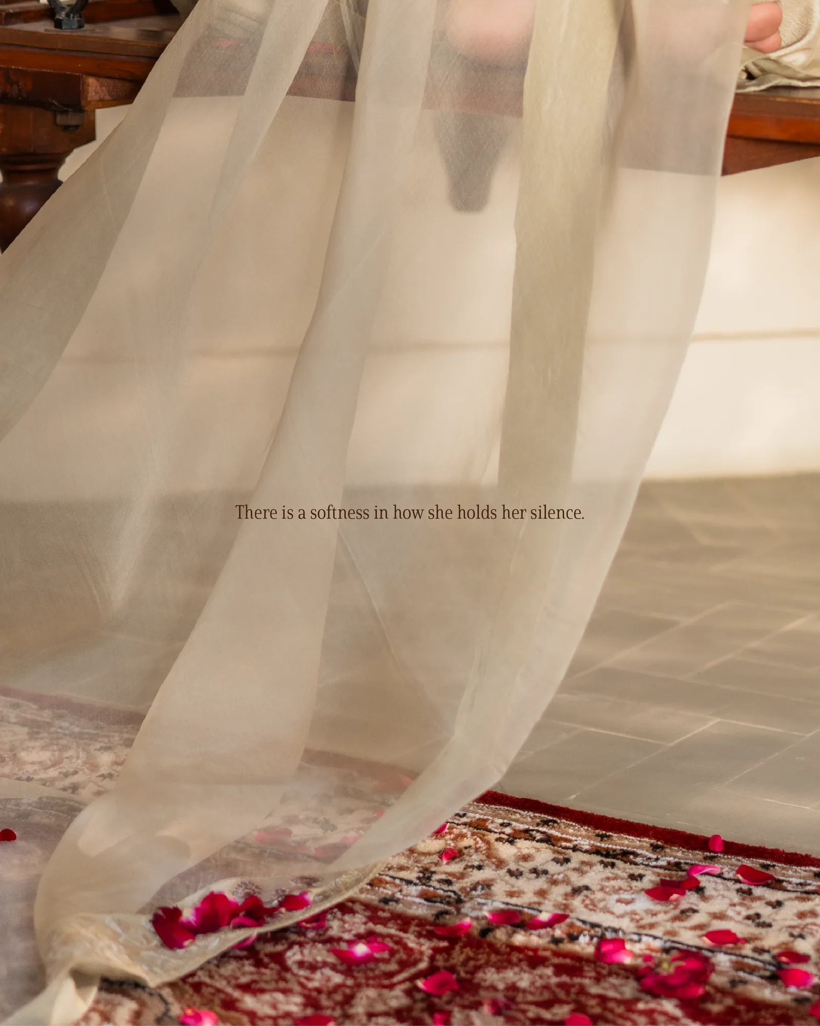 Sheer cream fabric moving over rose petals and carpet.