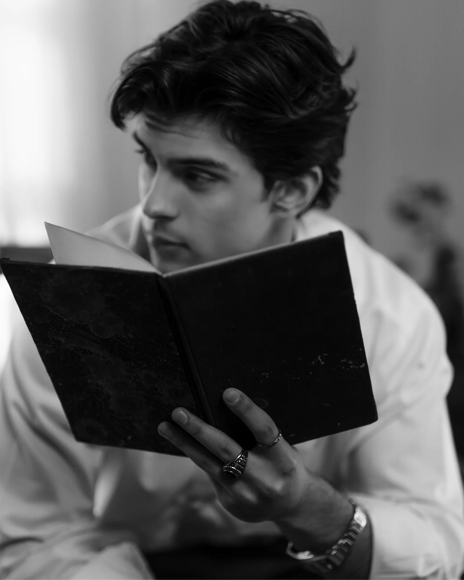 Black-and-white: the man reading, seen close in profile.