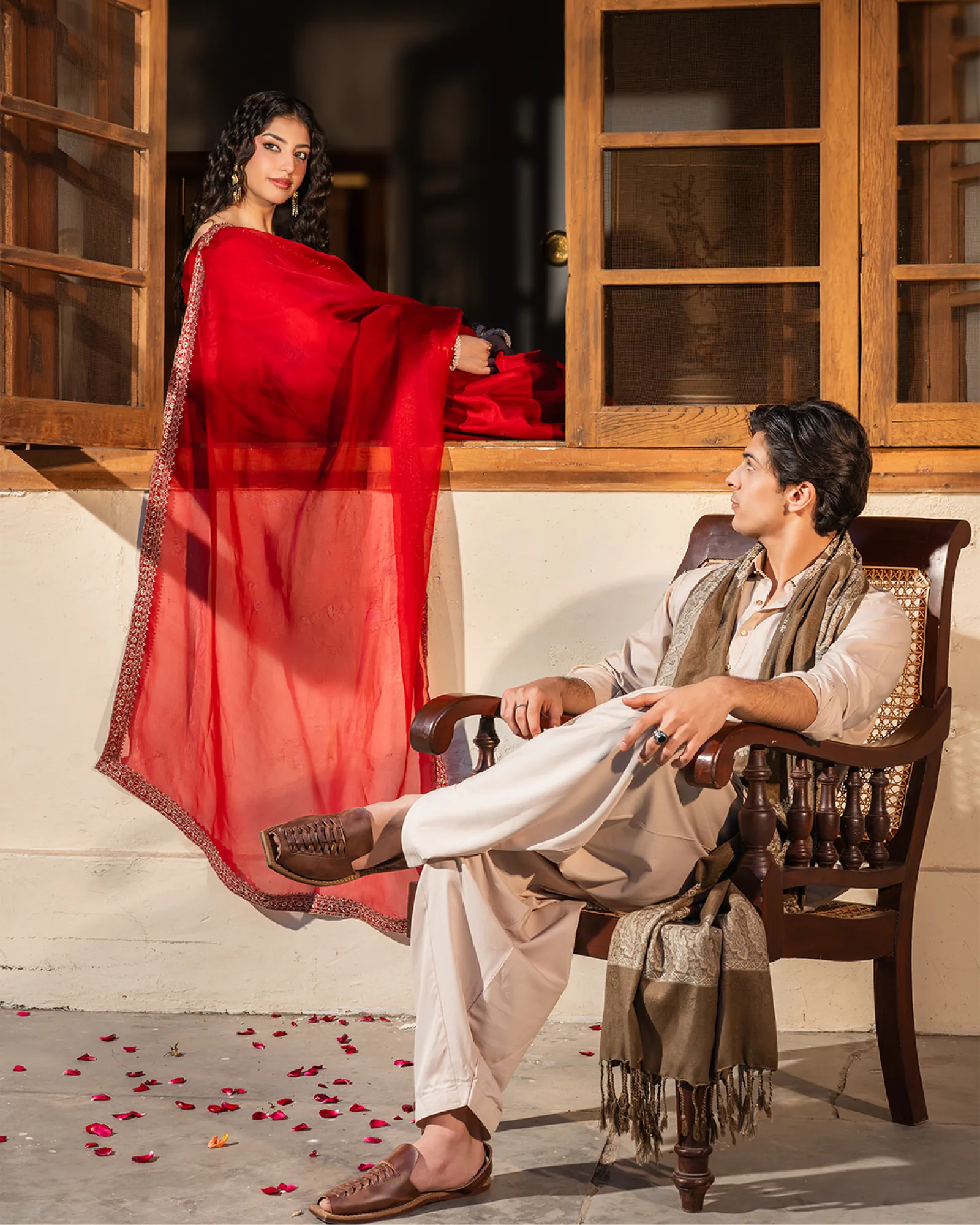 The woman in red on a window ledge and the man seated below looking up — the two worlds in one frame.